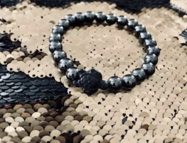 A black and silver bead bracelet on a sequined cloth.
