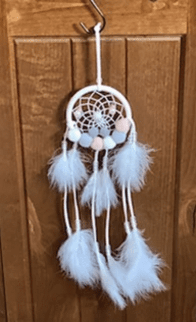 A white and pink dreamcatcher hanging on the wall.