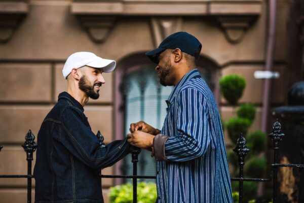 Two men shaking hands while holding onto a cane.