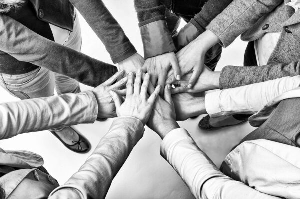 A group of people holding hands in the middle of a circle.