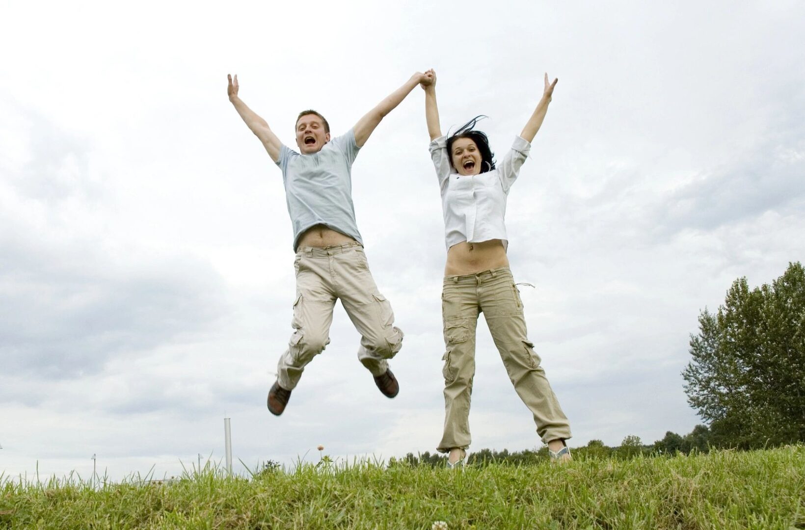 Two people jumping in the air on a hill